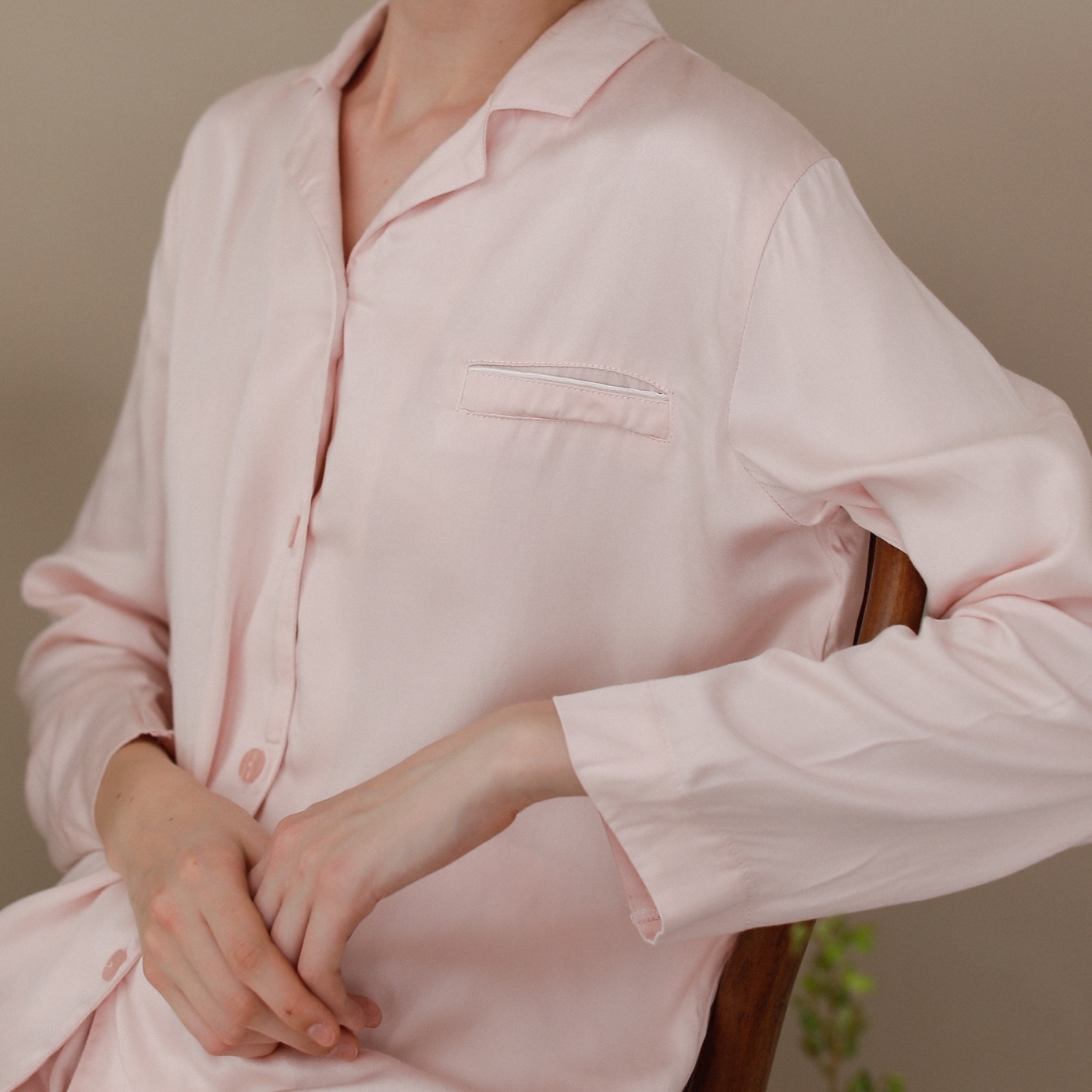 Close view of a pink pajama shirt showing its collar, chest pocket, buttons and sleeve finish